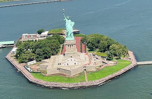 A statue of liberty on land with trees around it.